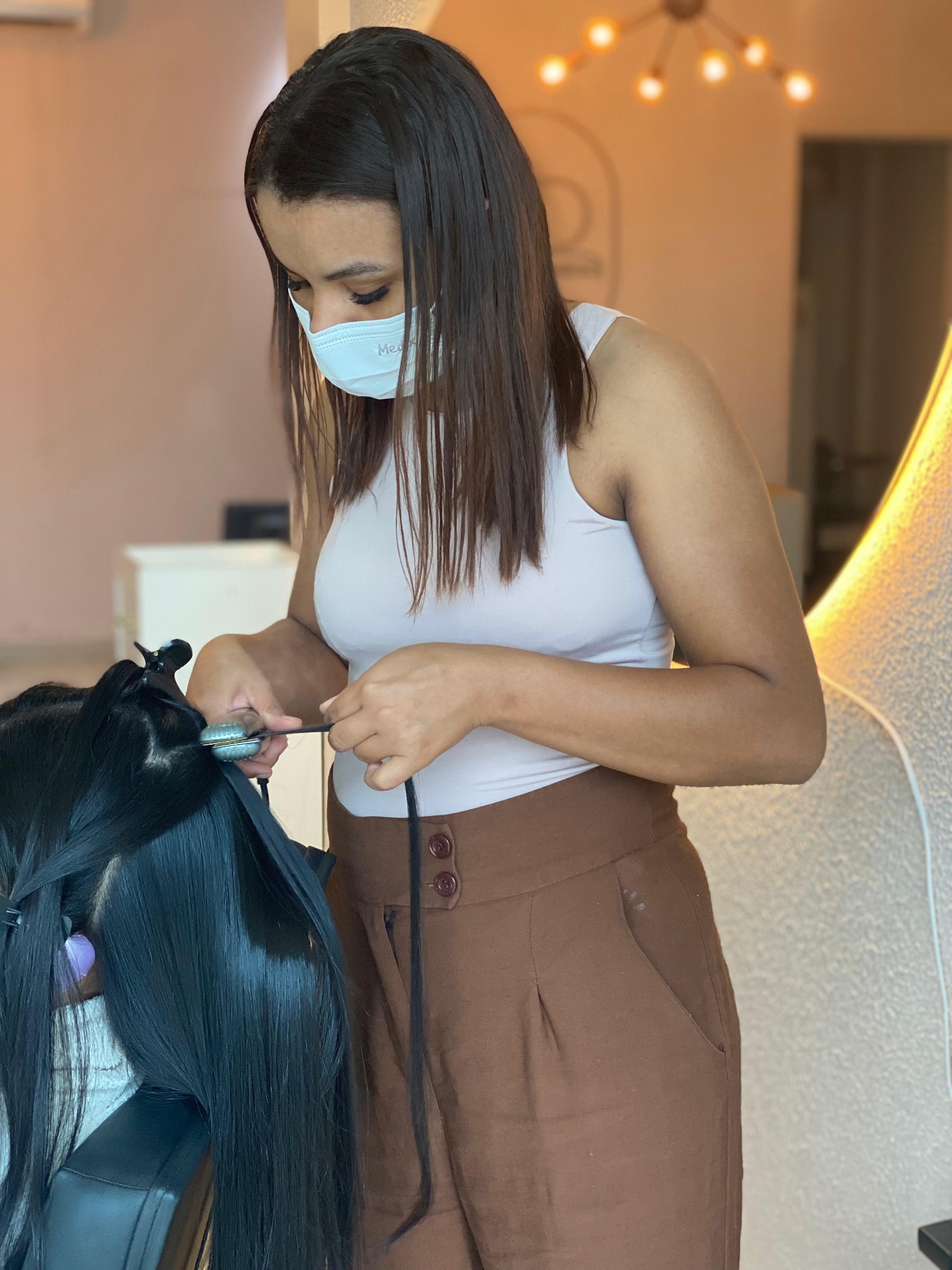 Rayane realizando um procedimento capilar em uma cliente